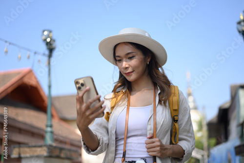 Attractive woman using mobile phone while walking and exploring city street during the day