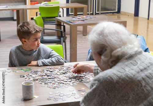 Elderly woman doing a puzzle with her great-grandson in a nursing home photo