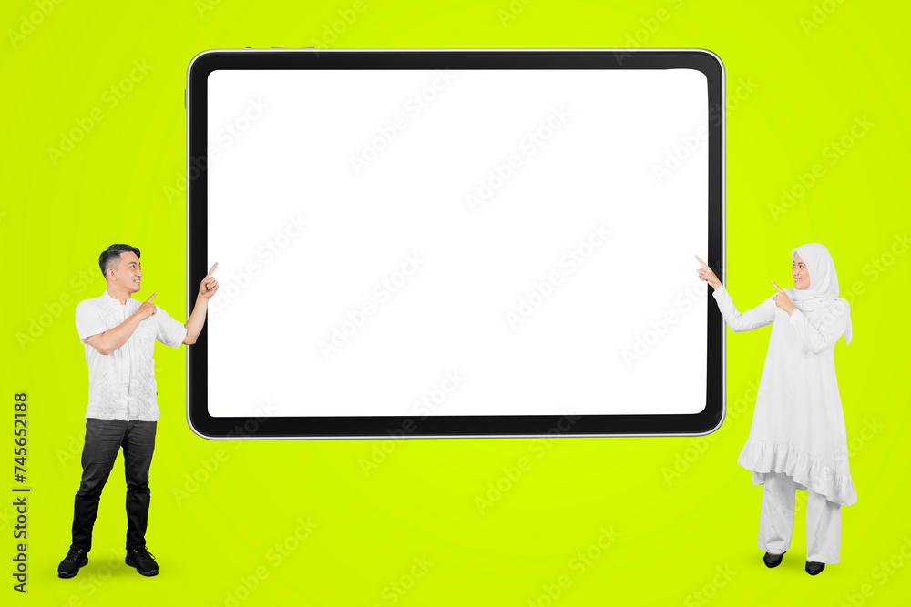 Cheerful muslim asian couple pointing at empty copyspace on a white board Cheerful muslim asian couple pointing at empty copyspace on a white board