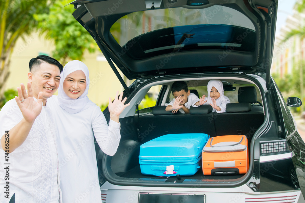 Happy muslim couple standing together at the back of the car
