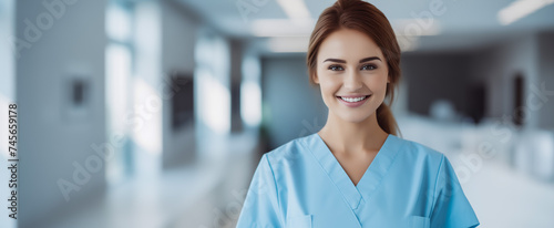 Smiling young female nurse in blue scrubs in hospital corridor