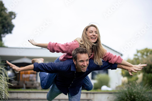 Cheerful man giving piggyback ride to woman in garden photo