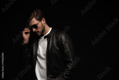 Fashion man, Handsome beauty male model portrait wear sunglasses and leather jacket, young guy over black background