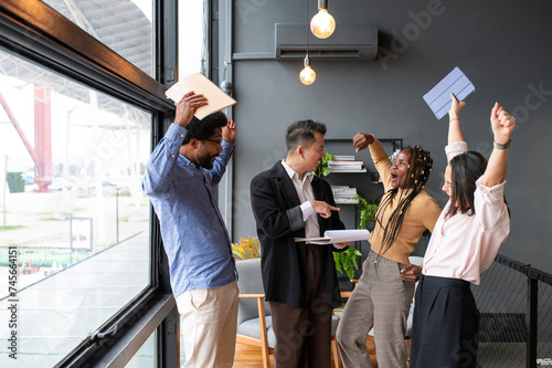 Happy businessman with colleagues cheering in office photo