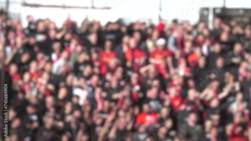 Many fans supporting soccer team at stadium. Blurred crowd of people at football stadium. Slow motion