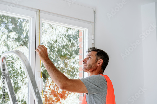 Mature technician measuring window at home photo