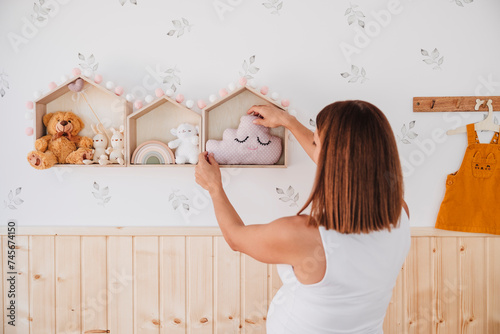 Pregnant woman decorating room with toys at home photo