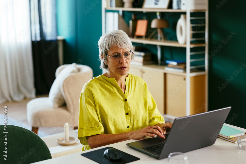 Mature freelancer working on laptop at home office Mature freelancer working on laptop at home office