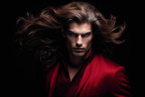 A striking male model in a bold crimson outfit, running a hand through his perfectly styled hair as he stands against a seamless black backdrop.