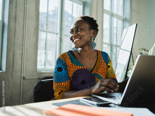 Smiling businesswoman with laptop at desk in office