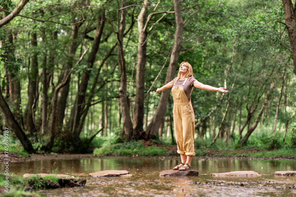 © Westend61 - Young woman standing with arms outstretched in forest
