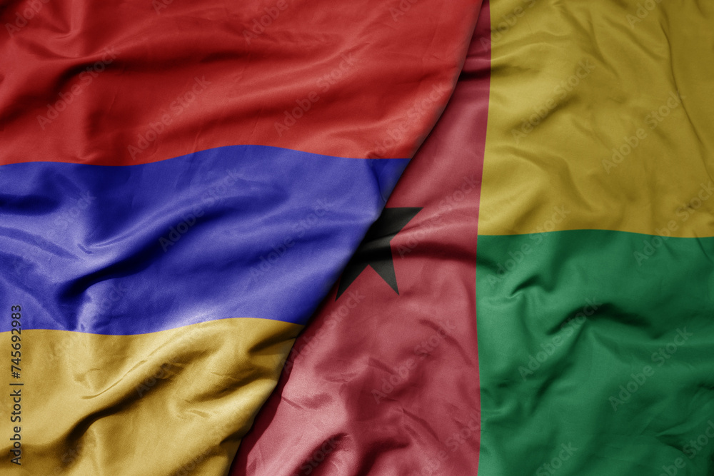 big waving national colorful flag of guinea bissau and national flag of armenia .