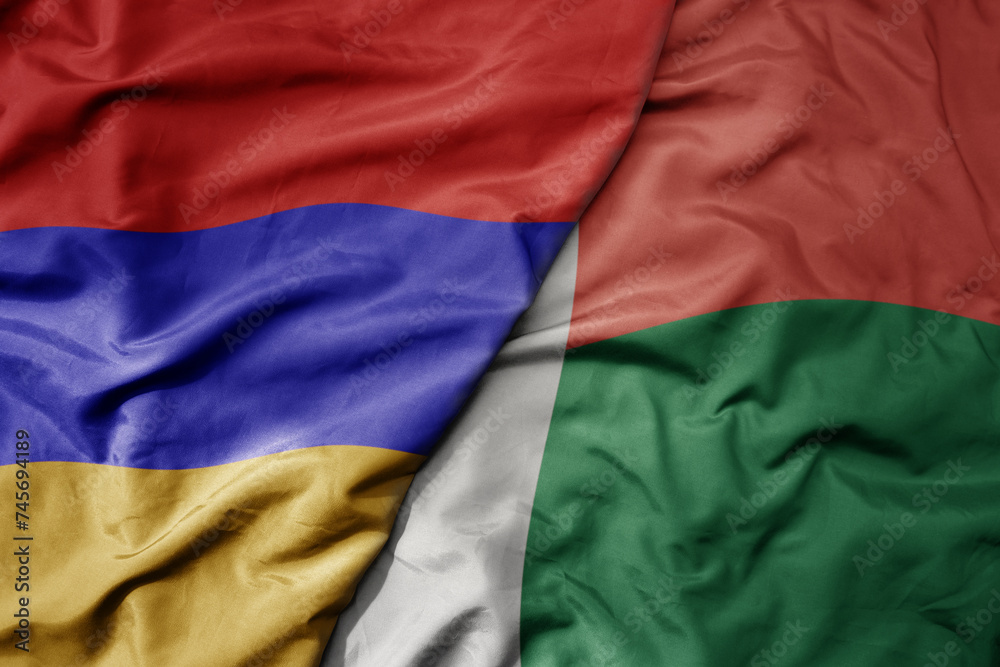 big waving national colorful flag of madagascar and national flag of armenia .