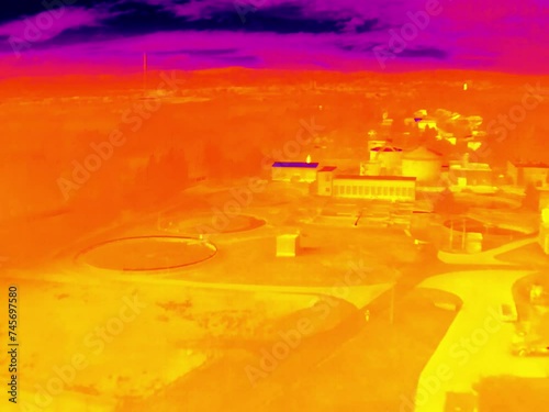 Aerial infrared thermal view of wastewater treatment plant with sedimentation tanks, in purple and yellow hues
 photo