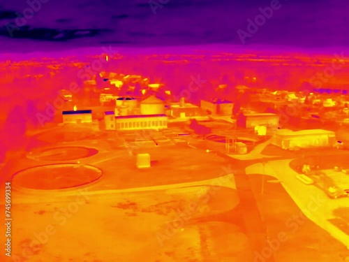 Aerial infrared thermal view of wastewater treatment plant with sedimentation tanks, in purple and yellow hues
 photo