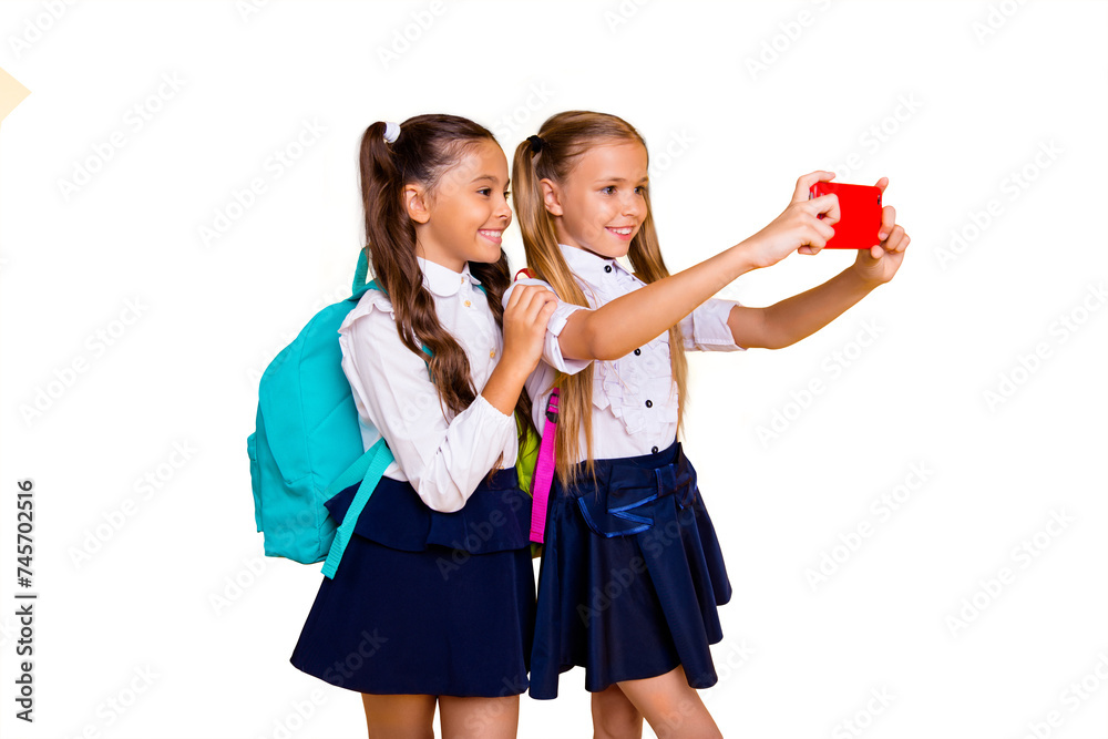Profile side view photo of two charming, gorgeous, adorable, good-looking small girls make selfie on smartphone camera isolated on shine yellow background Profile side view photo of two charming, gorgeous, adorable, good-looking small girls make selfie on smartphone camera isolated on shine yellow background