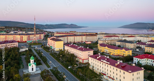 Panorama of the city of Magadan. Morning cityscape at dawn. Aerial view of streets, buildings, chapel and TV tower. In the distance is Nagaev bay and mountains. Magadan region, Far East of Russia.