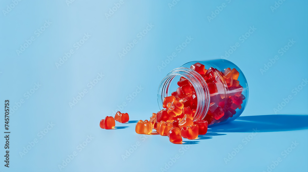 un pot de gummies rouges couché sur le côté avec gummies qui sortent du pot sur fond bleu - obrazy, fototapety, plakaty 