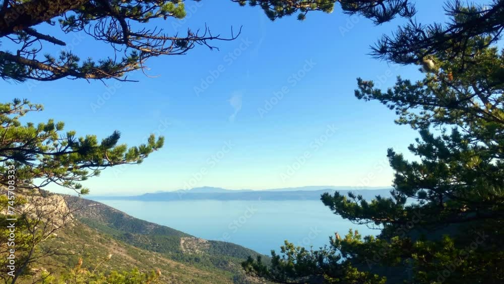 Looking through trees at a beautiful view of the ocean and mountains. Adriatic Sea. Dalmatia. Epic Panorama Ocean Scene. Dalmatian coast. Brac Island, Croatia. Europe. Looking through trees at a beautiful view of the ocean and mountains. Adriatic Sea. Dalmatia. Epic Panorama Ocean Scene. Dalmatian coast. Brac Island, Croatia. Europe.