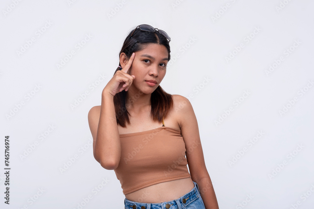 Fototapeta premium Attractive young Filipino woman pointing to her temple, portraying a sense of street smarts and confidence against a white background.