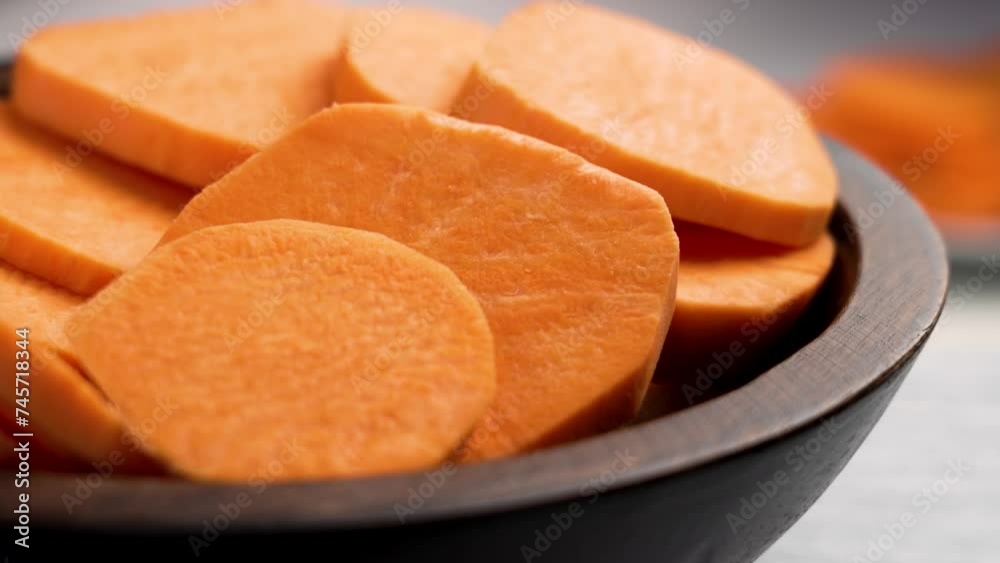 Sliced sweet potatoes in wooden kitchen bowl. Fresh vegetable ingredients close up. Rotation Sliced sweet potatoes in wooden kitchen bowl. Fresh vegetable ingredients close up. Rotation