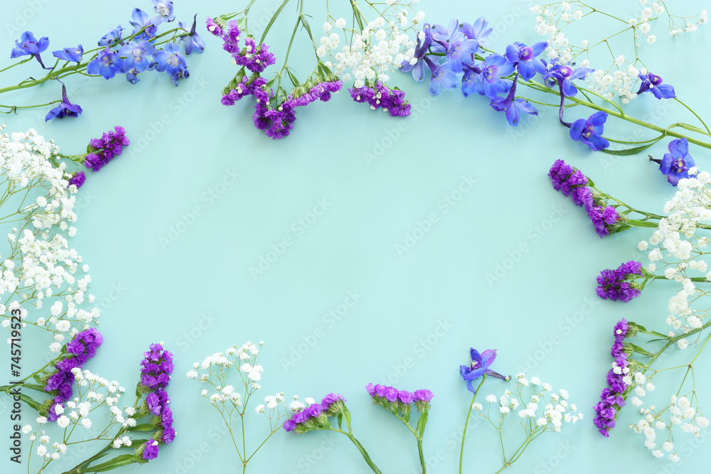 Top view image of violet delphinium flowers composition over mint background