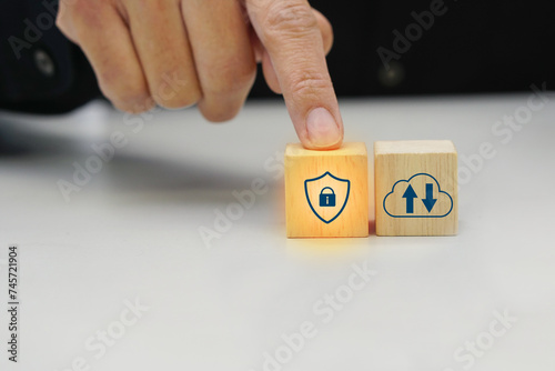 Businessman touching a wooden block cube with various icon symbol. Safety protection, technology and online insurance concept.