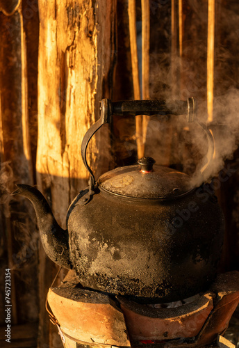 Old kettle on flaming fire with steam boiling water and nature background in morning time