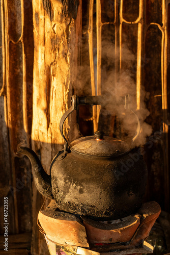 Old kettle on flaming fire with steam boiling water and nature background in morning time