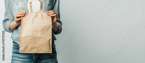 Female hand holds brown craft paper bag for takeaway on white background. Generated AI image