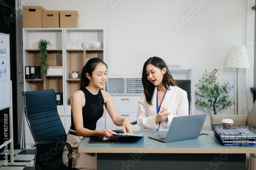 Businesswomen work and discuss their business plans. A Human employee explains and shows her colleague the results paper