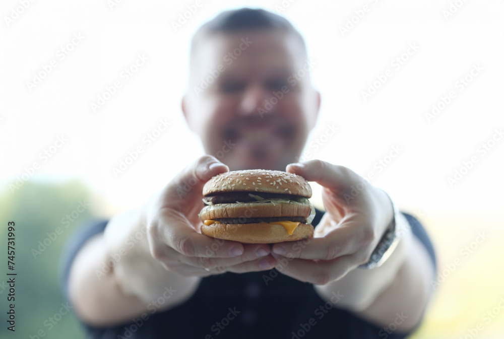 Satisfied young man holding a hamburger
