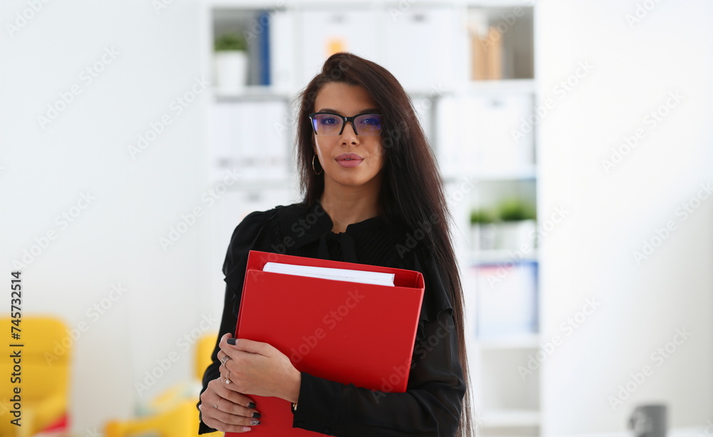 Beautiful smiling brunette woman hold in arms red binder Beautiful smiling brunette woman hold in arms red binder
