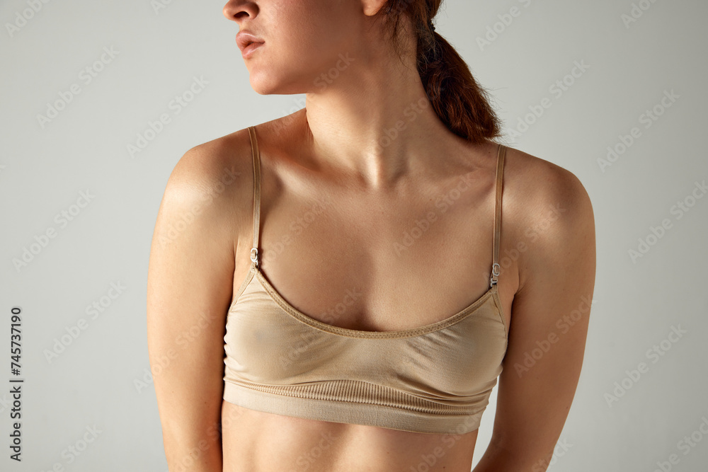 Female health. Cropped image of young woman, breast in underwear against grey studio background. Be aware of female illness. Concept of body and health care, female beauty, wellness Female health. Cropped image of young woman, breast in underwear against grey studio background. Be aware of female illness. Concept of body and health care, female beauty, wellness