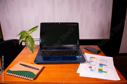 office concept. laptop in writing with cell phone and business graphics