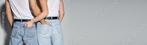 back view of man and woman in blue casual jeans posing with hands in pockets, sexy couple, banner