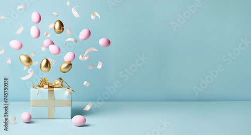 Easter eggs of gold and pink color flying out of a gift box on a blue background, minimal creative Easter layout for congratulations. Banner with copy space for text. Greeting card photo