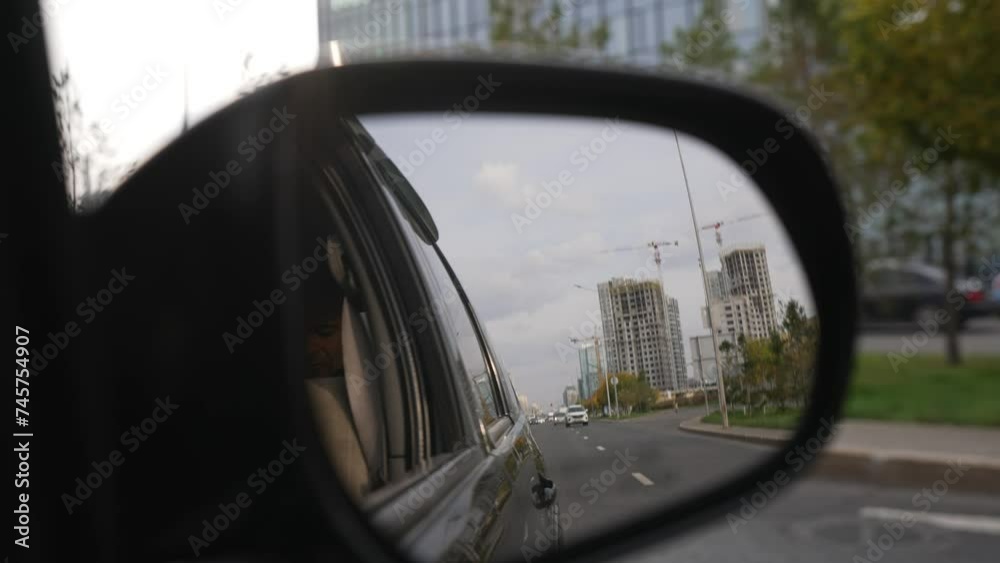 Car's mirror view. Buildings view in the rear view side mirror of a auto. Road on a side mirror. Side view mirror road marks and tar road with overtaking car. Car's mirror view. Buildings view in the rear view side mirror of a auto. Road on a side mirror. Side view mirror road marks and tar road with overtaking car.