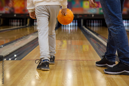 Rear view of teenager boy and father holding bowling ball while standing in bowling alley in shooting position © Yelena