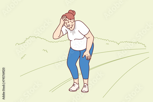 Tired woman runner takes break due to weak cardio system or leg pain, standing at stadium or park. Girl runner leads active lifestyle to lose weight and improve heart and lung health.