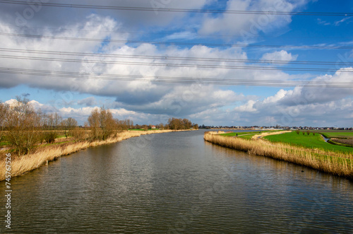 View under electricity wires of the river Rotte in the Netherlands, with water levels a few meters higher than the surrounding polder