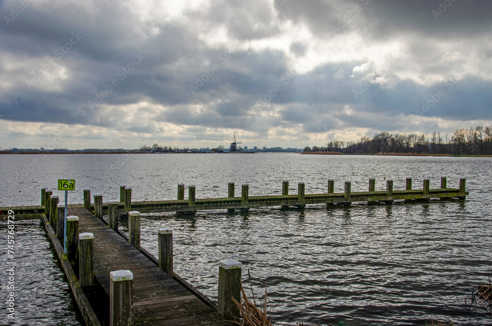 Wooden jetty on the bank of the river Rotte in the Netherlands under a dramatic sky