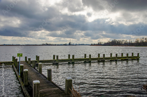 Wooden jetty on the bank of the river Rotte in the Netherlands under a dramatic sky © Frans