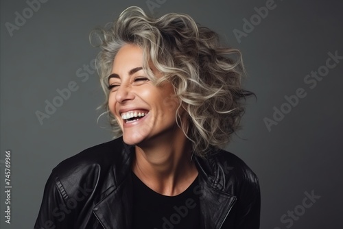Portrait of a beautiful smiling woman in leather jacket over grey background