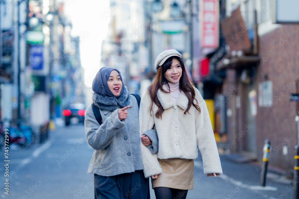 woman girl tourist Two Asian friends but different religions, one of whom is a Muslim girl. Walking tour of the city, city view, traveling in Japan Tokyo. with fun She is traveling in the city area. woman girl tourist Two Asian friends but different religions, one of whom is a Muslim girl. Walking tour of the city, city view, traveling in Japan Tokyo. with fun She is traveling in the city area.