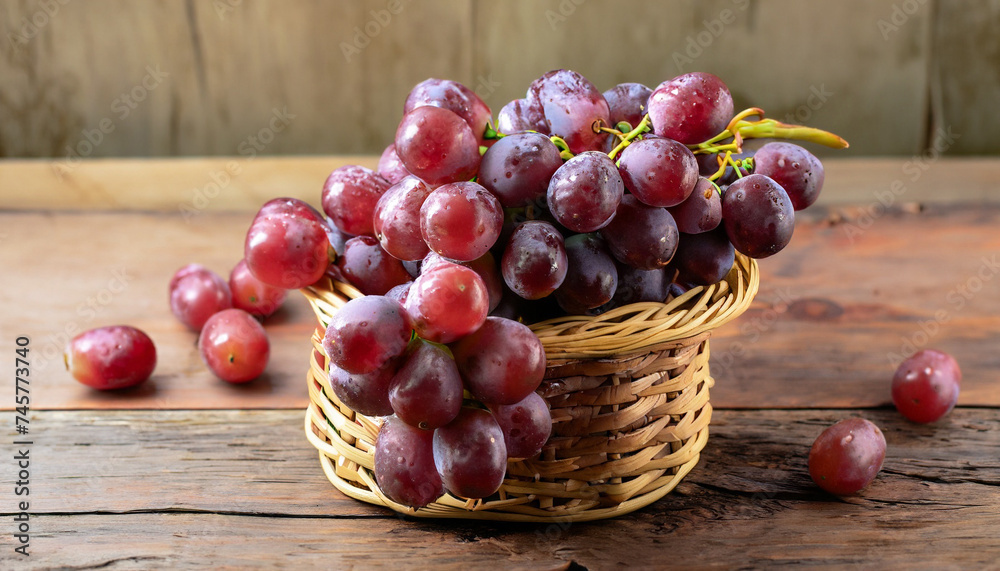Red grapes, naturally sweet fruit, are placed on a wooden table and arranged in a wooden basket. on the old wooden background Red grapes, naturally sweet fruit, are placed on a wooden table and arranged in a wooden basket. on the old wooden background