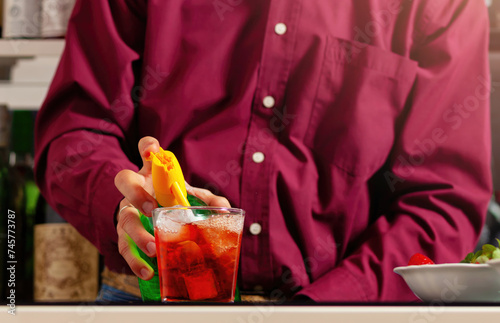 Man in magenta shirt preparing colorful cocktail