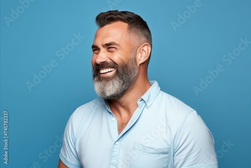 portrait of handsome middle aged man smiling at camera on blue background