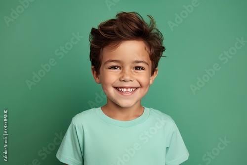 Cheerful little boy in casual t-shirt on green background