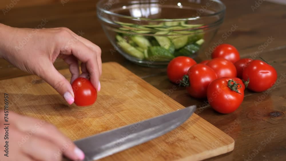 A woman is slicing tomatoes on the table. Tomatoes are being cut neatly, revealing their vibrant red color. She skillfully handles each tomato, preparing them for a delicious dish.